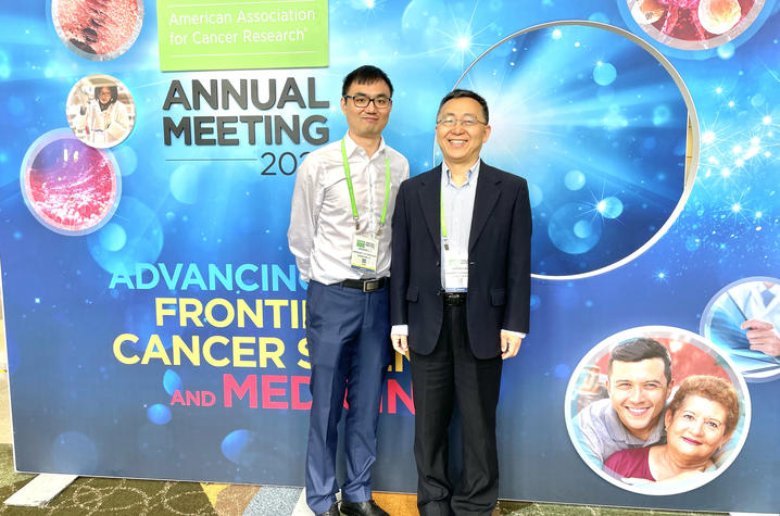 Markey researchers Jinghui Liu and Xiaoqi Liu at the 2023 AACR conference, standing in front of an event banner wall.