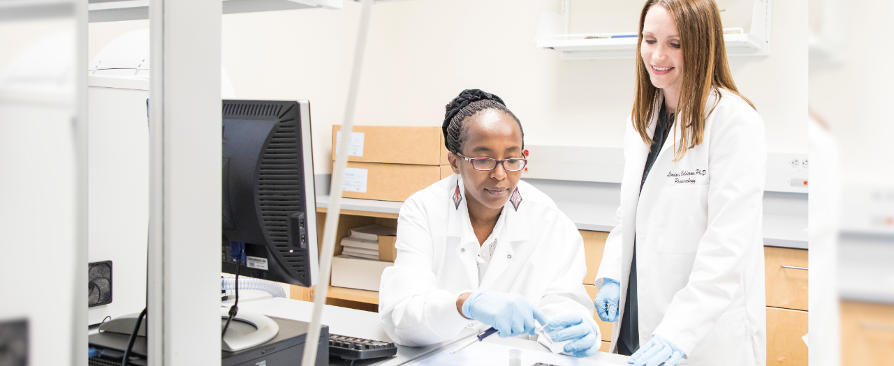 Drs. Ndinguri and Cormier in lab coats conducting research